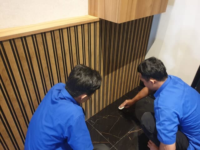 Petugas membersihkan dinding panel kayu