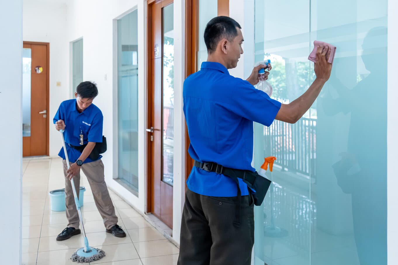 Petugas membersihkan kaca dan lantai koridor kantor