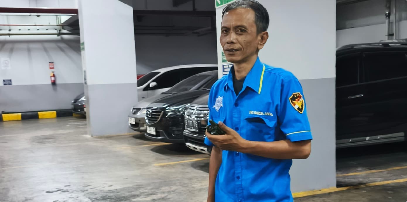 Petugas Tri Garda Abbas menjaga area parkir basement gedung
