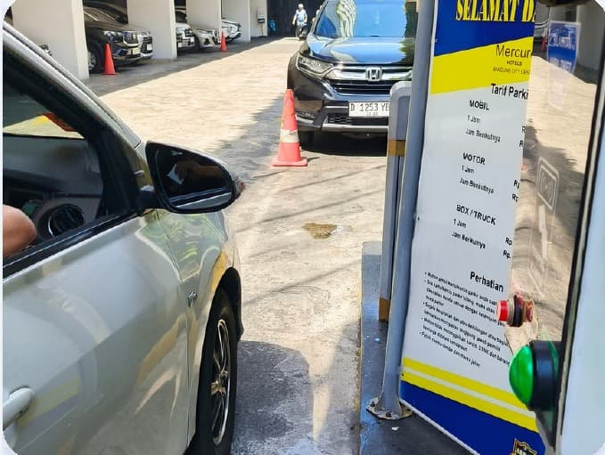 Papan tarif parkir dan proses tap pembayaran di gerbang keluar